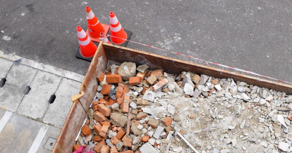 A birds-eye view of a dumpster loaded with debris. Some of the debris includes bricks, concrete, and metal.